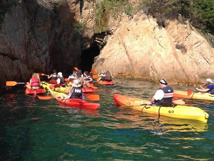 A group of kayakers exploring a cave entrance