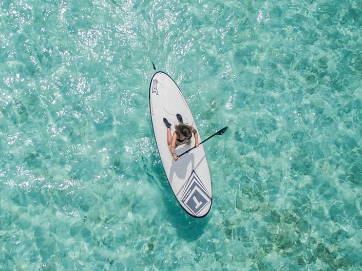 Stand up paddle boarding, girl kneeling on paddle board