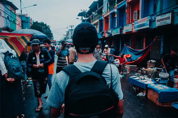 person with backpack walking through a market 